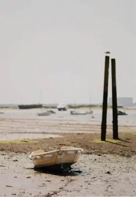 a boat sitting on a beach next to two poles at The retreat in West Mersea