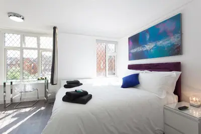 a white bedroom with a large white bed and windows at The Orlando in Cambridge