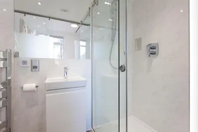 a white bathroom with a shower and a sink at The Orlando in Cambridge