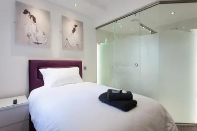 a bedroom with a white bed and a glass shower at The Orlando in Cambridge