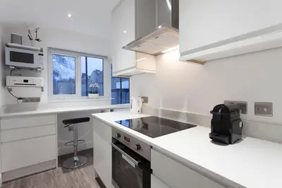 a white kitchen with a sink and a stove at The Orlando in Cambridge