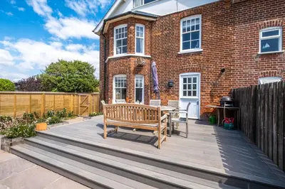 a wooden deck with a bench in front of a brick building at Lower Saltings in Aldeburgh