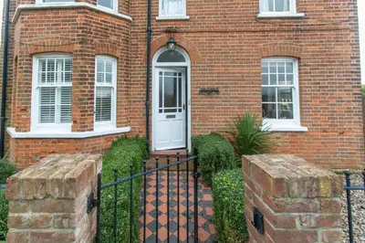 a brick house with a white door and a fence at Lower Saltings in Aldeburgh