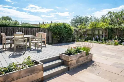 a patio with a table and chairs in a garden at Lower Saltings in Aldeburgh
