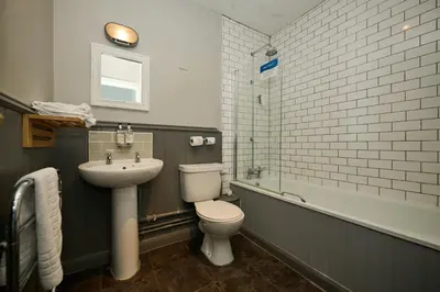 a bathroom with a sink and a toilet and a tub at White Hart, Newmarket by Marston's Inns in Newmarket