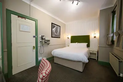 a hotel room with a bed and a door at White Hart, Newmarket by Marston's Inns in Newmarket