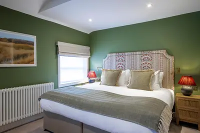 a bedroom with a large bed with green walls at The Bell Hotel, Saxmundham in Saxmundham