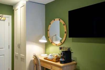 a mirror on a green wall next to a table at The Bell Hotel, Saxmundham in Saxmundham