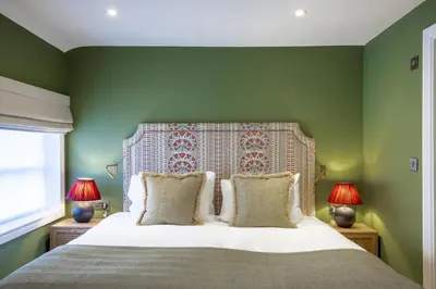 a bedroom with green walls and a bed with two lamps at The Bell Hotel, Saxmundham in Saxmundham