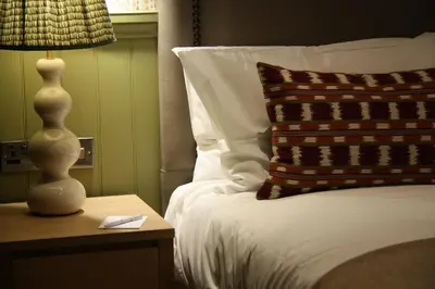a bed with a red pillow and a lamp on a table at The Bell Hotel, Saxmundham in Saxmundham