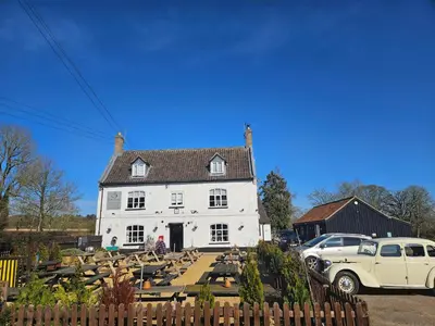 a white house with a car parked in front of it at The Swan Inn in Hilborough