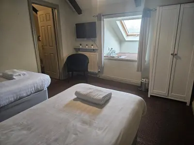 a hotel room with two beds and a window at The Swan Inn in Hilborough