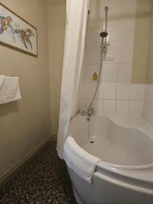 a bath tub in a bathroom with a shower at The Swan Inn in Hilborough