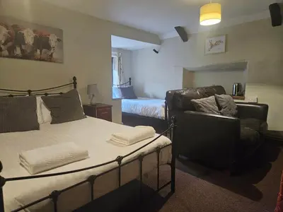 a bedroom with a bed and a couch and a chair at The Swan Inn in Hilborough