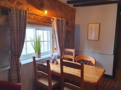 a dining room with a wooden table and a window at The Swan Inn in Hilborough