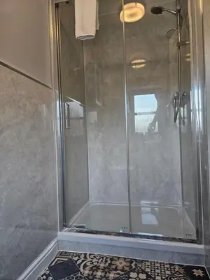 a shower with a glass door in a bathroom at The Swan Inn in Hilborough