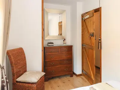 a bedroom with a dresser and a mirror and a chair at The Haybarn in West Bradenham