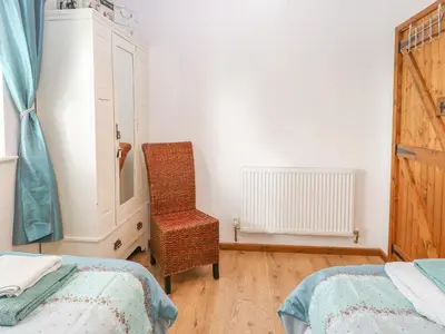 a bedroom with two beds and a chair and a dresser at The Haybarn in West Bradenham