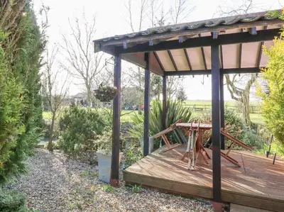 a wooden deck with a gazebo in a garden at The Haybarn in West Bradenham