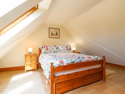 a bedroom with a wooden bed in a attic at The Studio, Horseshoe Cottage in Fulbourn