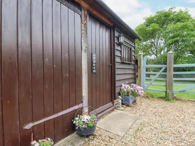 a wooden fence with two potted flowers next to a barn at The Studio, Horseshoe Cottage in Fulbourn