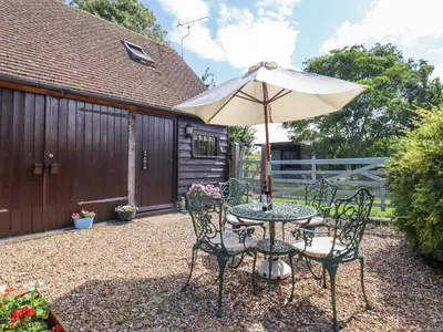 a patio table and chairs with an umbrella at The Studio, Horseshoe Cottage in Fulbourn