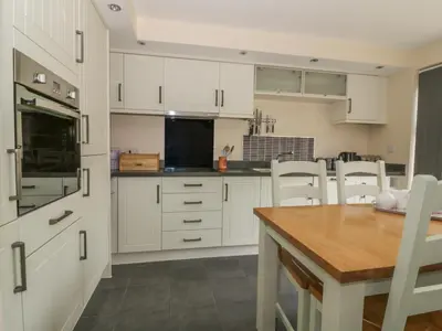 a kitchen with white cabinets and a wooden table at Sandlings in Hollesley