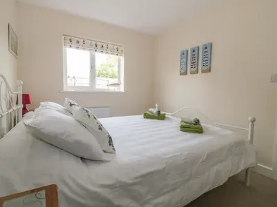a white bed with white pillows and a window at Sandlings in Hollesley