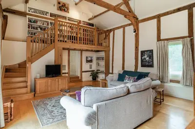 a living room with two couches and a staircase at Ducksfoot Barn in Pulham Saint Mary Magdalene