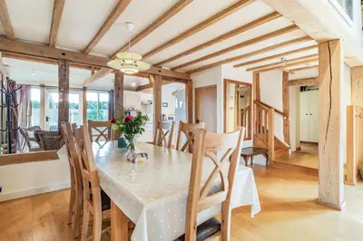 a dining room and living room with a table and chairs at Ducksfoot Barn in Pulham Saint Mary Magdalene
