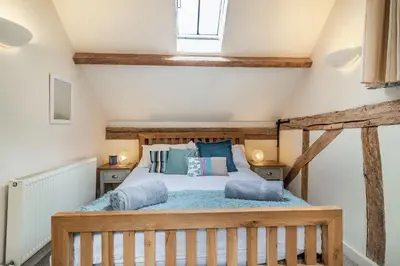a bedroom with a wooden bed with blue pillows at Ducksfoot Barn in Pulham Saint Mary Magdalene