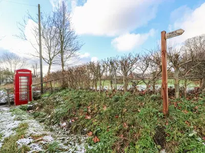 a red phone booth next to a street sign at 28 Oxborough in Oxborough