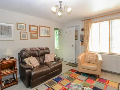 a living room with a leather couch and a chair at Peggotty's in Kelsale