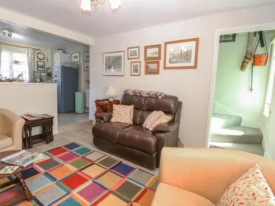 a living room with a leather couch and a rug at Peggotty's in Kelsale