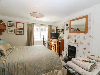 a bedroom with a bed and a fireplace and a mirror at Peggotty's in Kelsale