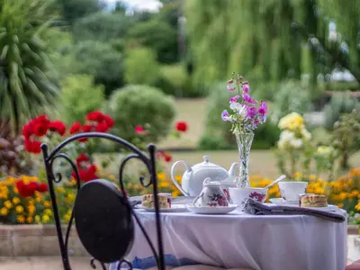 a table with tea and a vase of flowers on it at Norbank Cottage in Bressingham