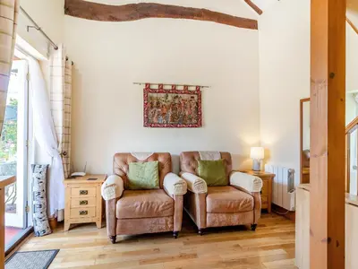 a living room with two chairs and a table at Norbank Cottage in Bressingham