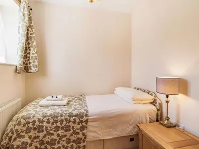 a small bedroom with a bed and a lamp at Punch Cottage in Little Glenham