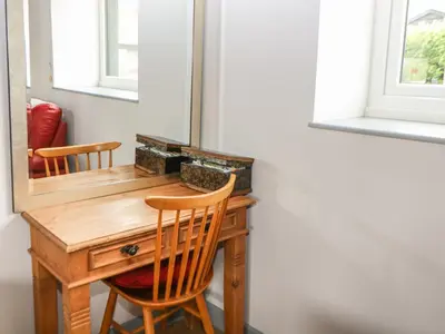 a wooden desk with two chairs and a mirror at Snowy Owl Barn in Shipdham