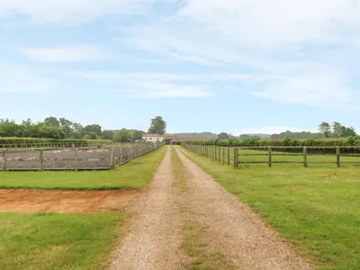 a dirt road in a field with a fence at Snowy Owl Barn in Shipdham