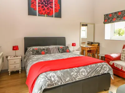 a bedroom with a bed with a red blanket at Snowy Owl Barn in Shipdham