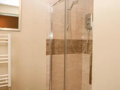 a shower stall with a glass door in a bathroom at Tawny Owl Barn in Shipdham