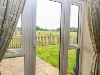 an open door with a view of a field at Tawny Owl Barn in Shipdham