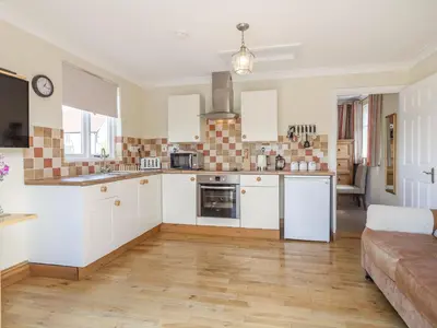a kitchen with white cabinets and a couch at Norbank Garden Studio in Bressingham