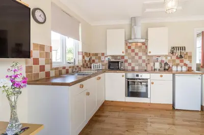 a kitchen with white cabinets and a clock on the wall at Norbank Garden Studio in Bressingham