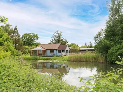 a house with a pond in front of it at Dragonfly Lodge in Yaxham
