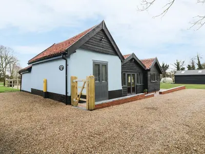 a cottage with a playground in front of it at Whitehands Farm Barn in Old Buckenham