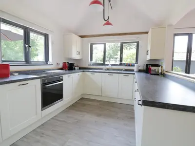 a white kitchen with white cabinets and windows at Whitehands Farm Barn in Old Buckenham