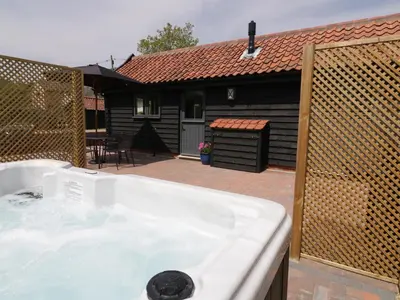 a bath tub in front of a house at Whitehands Farm Barn in Old Buckenham