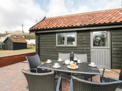 a table and chairs on the patio of a house at Whitehands Farm Barn in Old Buckenham